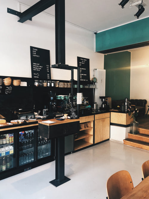 Professional coffee training center interior showing barista station with espresso machines, grinders, and brewing equipment in modern open space