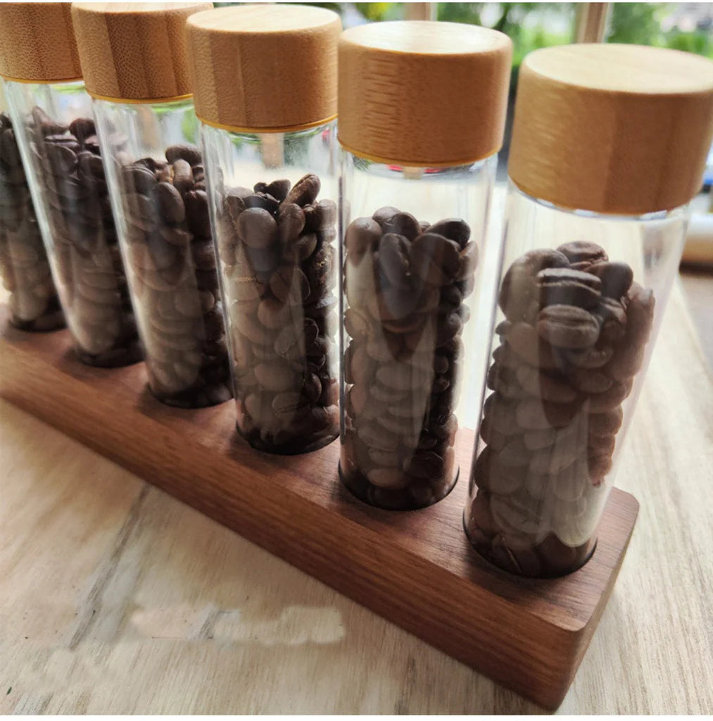 Set of glass bottles with wooden lids containing stones on a wooden stand.