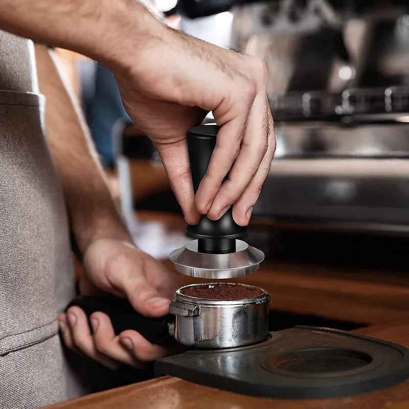 Person using a coffee tamper to compress coffee grounds in a portafilter.