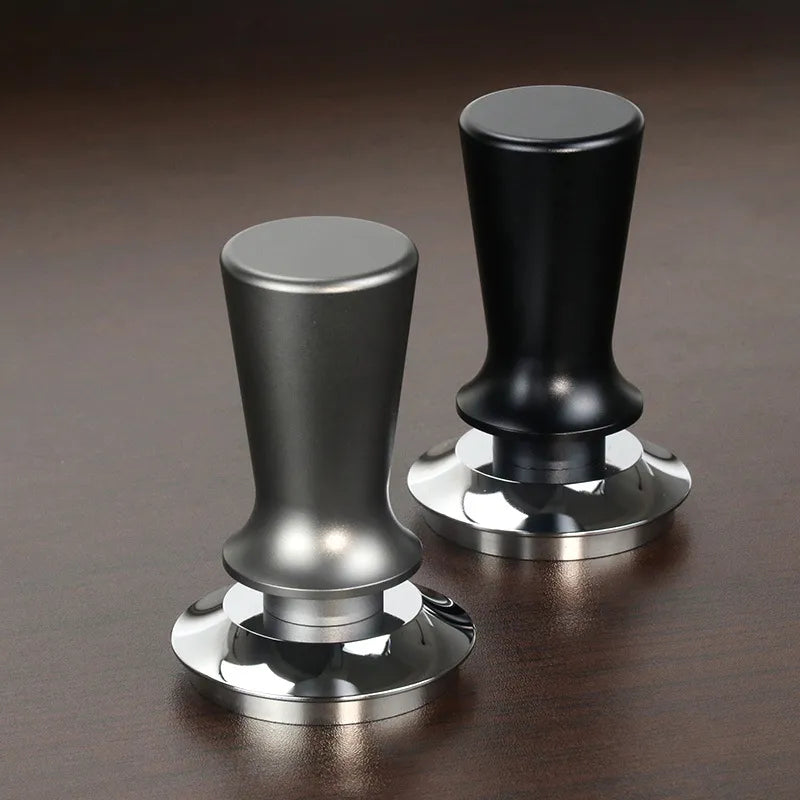 Two coffee tampers, one black and one silver, on a dark surface.