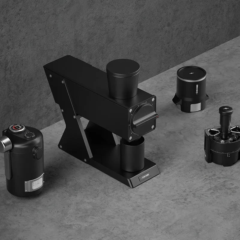 Black coffee grinder and accessories on a gray surface