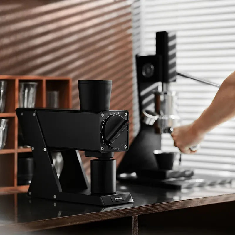 Black coffee grinder on a counter with a blurred background of a kitchen.