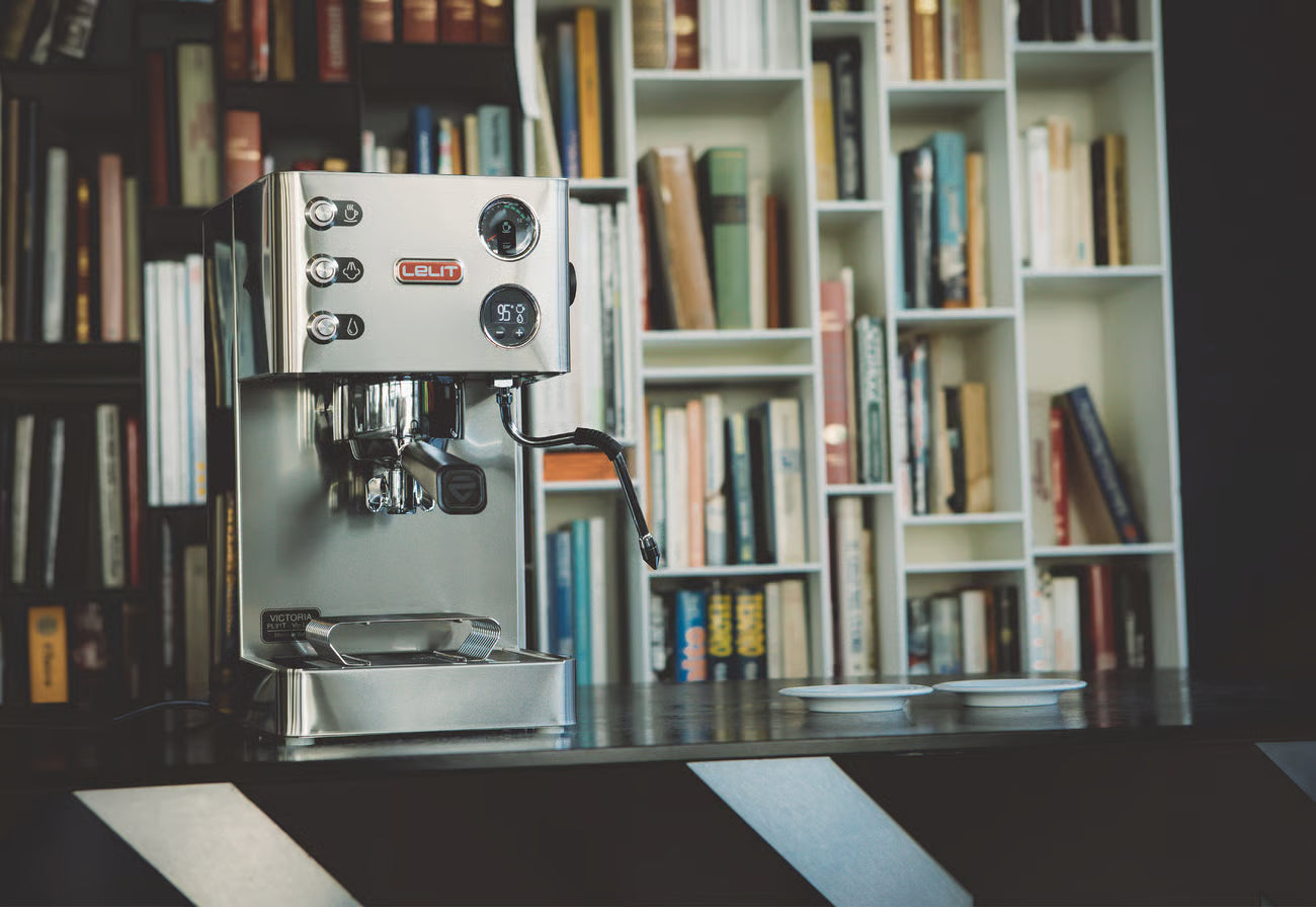 Silver espresso machine on a table with a bookshelf in the background