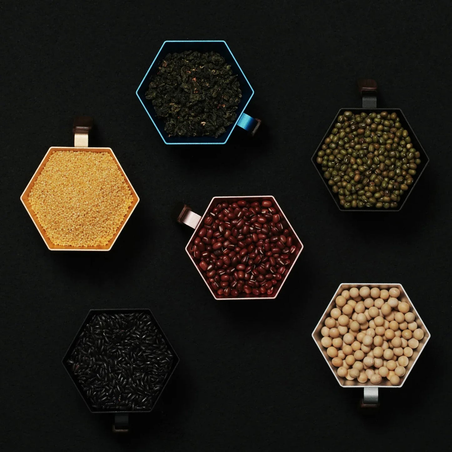 Hexagonal containers with various seeds on a black background