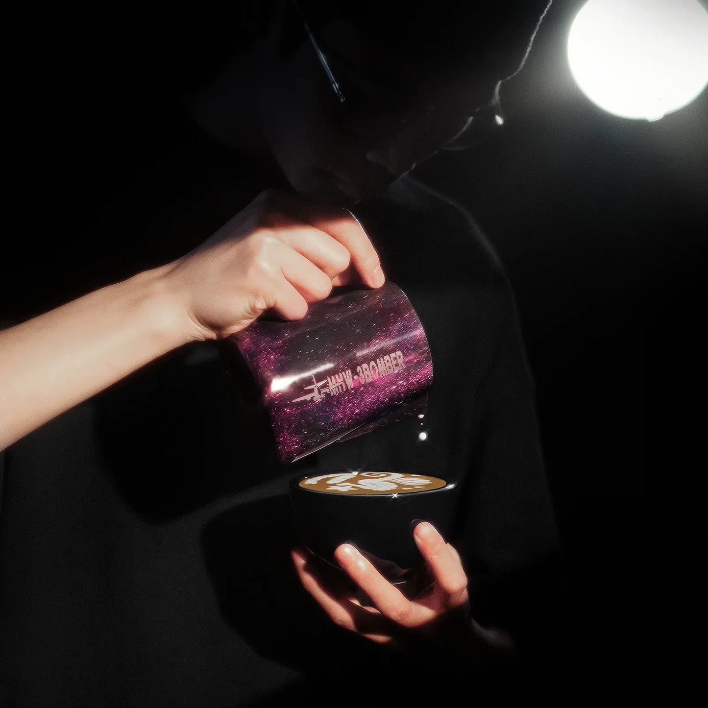 Person pouring a drink from a purple mug into a black cup with a dark background