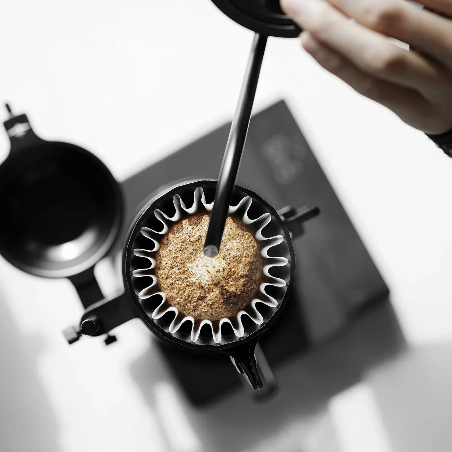 Coffee brewing process with a black coffee filter and grounds.