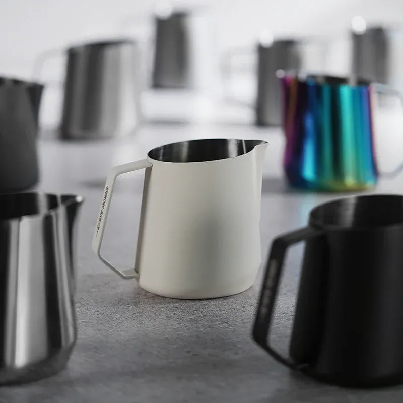 Set of milk pitchers on a gray surface with blurred background