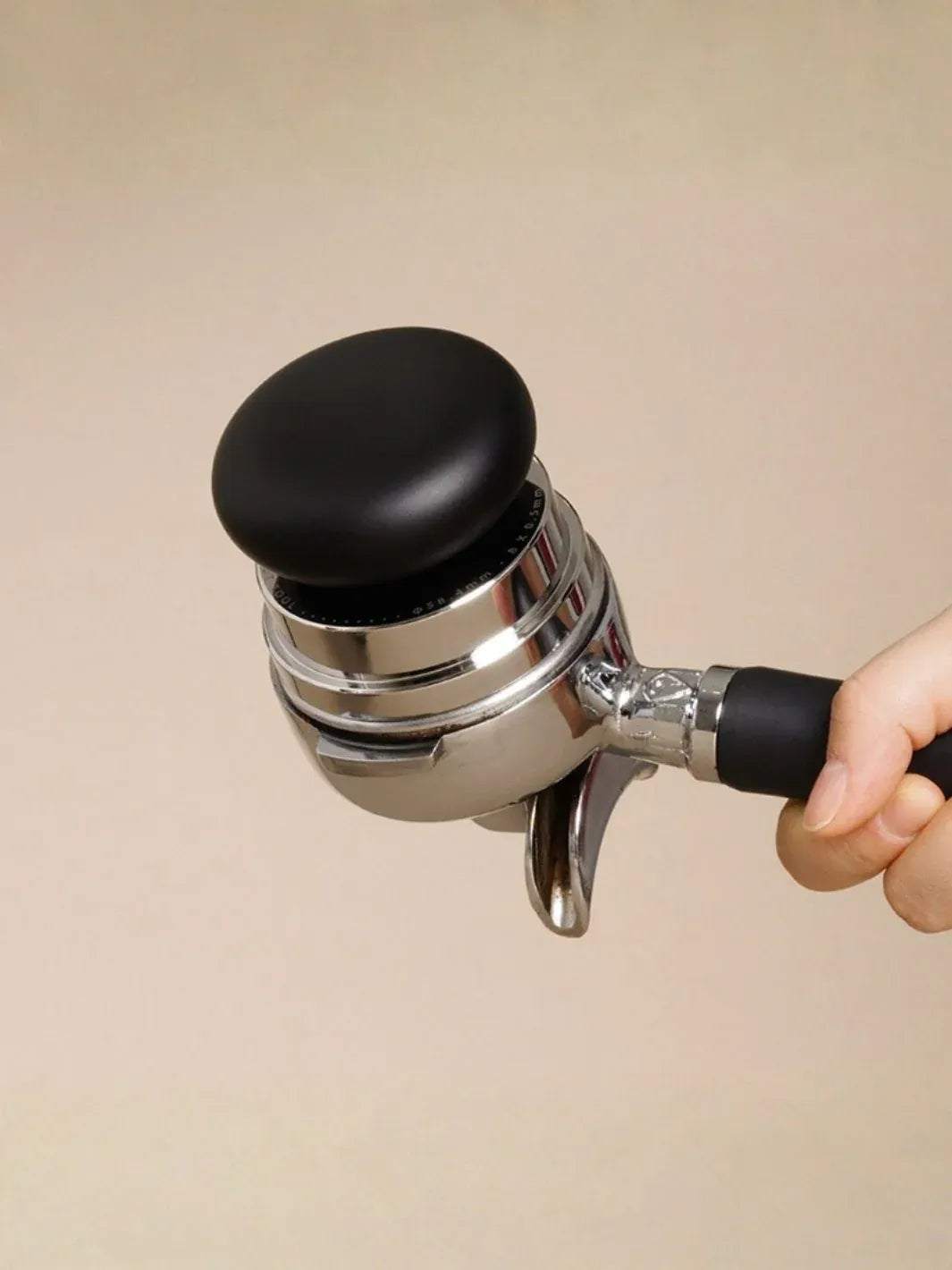 Coffee grinder with black top and handle on a beige background