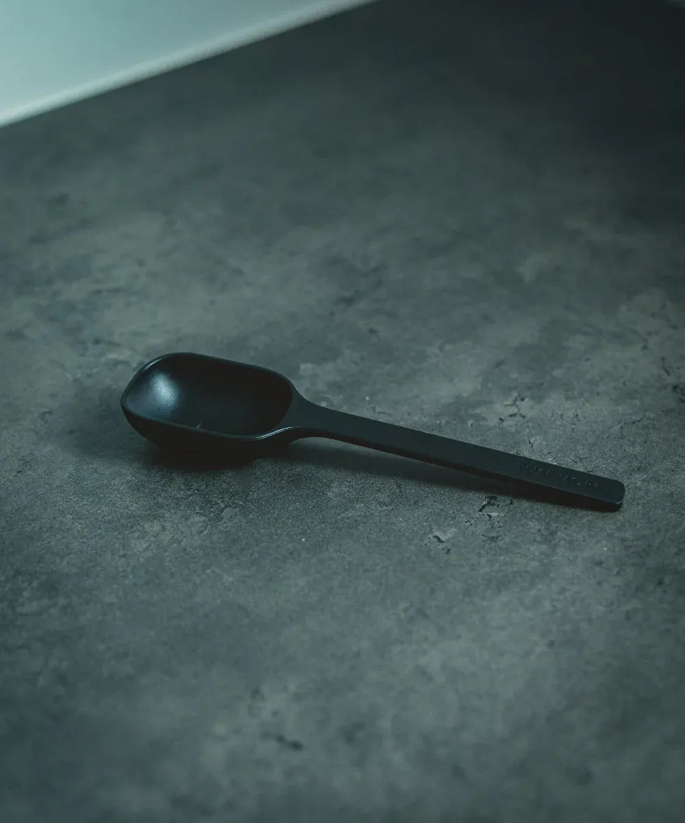 Black spoon on a textured gray surface