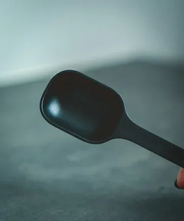 Black spatula held against a gray background