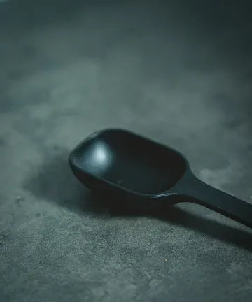 Black plastic scoop on a textured gray surface