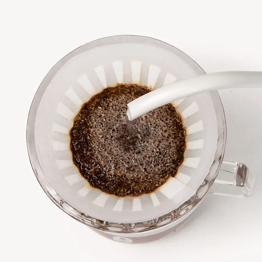 Coffee being poured into a glass filter on a white background