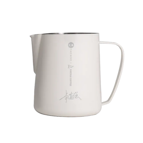 Stainless steel milk pitcher with handle on a white background