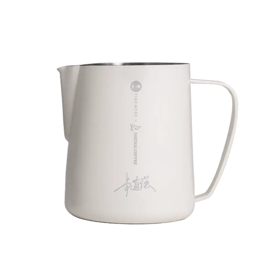 Stainless steel milk pitcher with handle on a white background