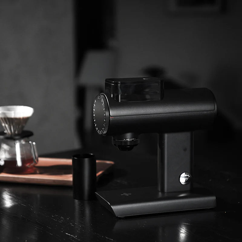 Black coffee grinder on a dark surface with a blurred background