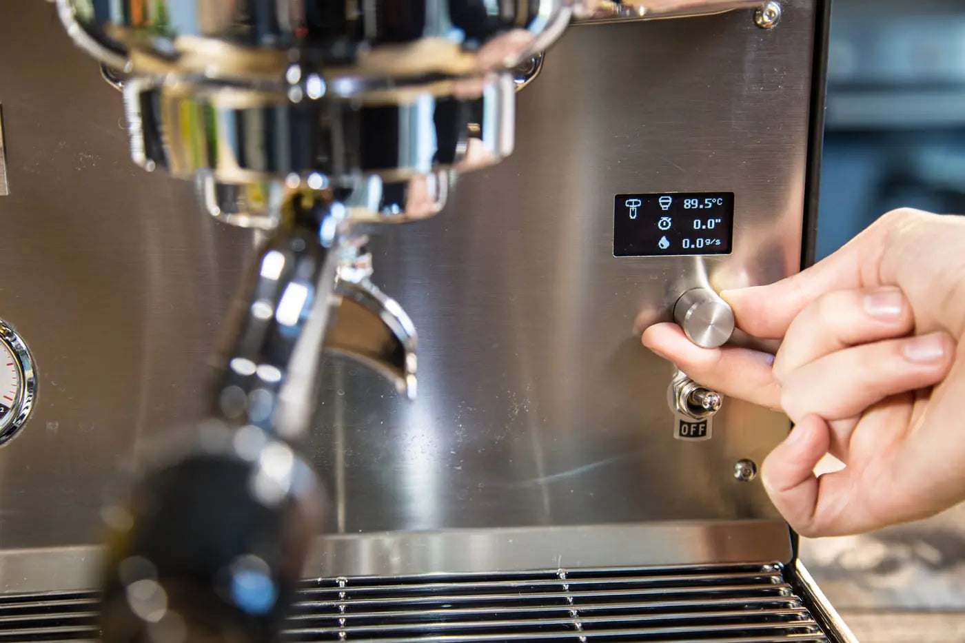 Close-up of professional barista tamping espresso grounds into portafilter attached to Dalla Corte Studio group head