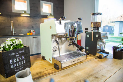 Side view of Dalla Corte Studio espresso machine on espresso bar with coffee equipment and accessories visible