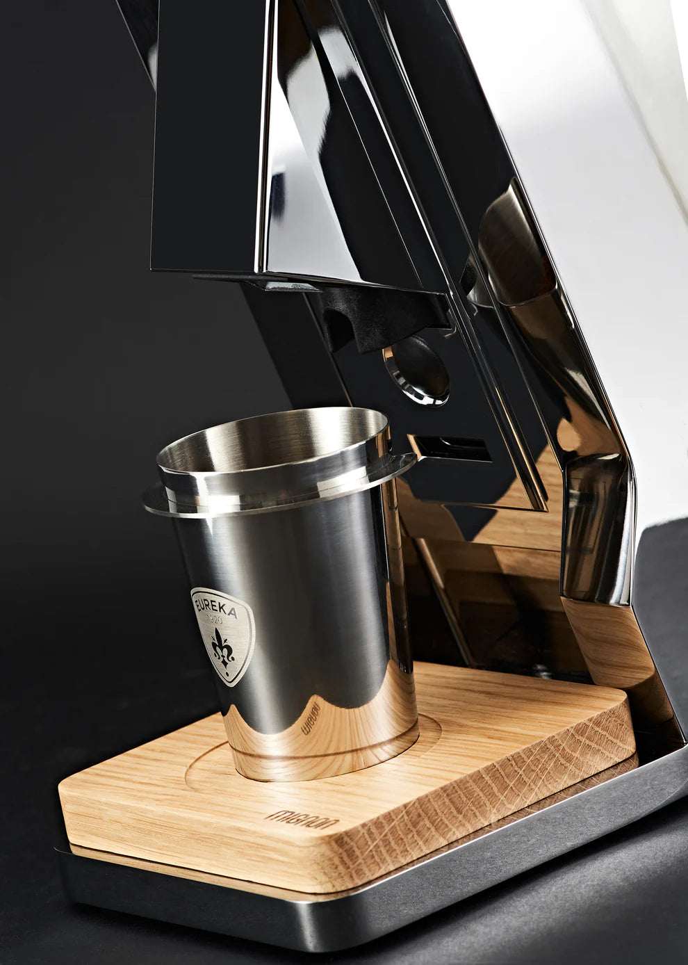 Eureka dosing cup positioned under espresso grinder chute for coffee collection.
