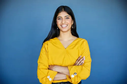 files/smiling-young-businesswoman-standing-with-crossed-arms-by-a-blue-wall-in-an-office.webp