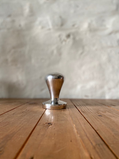 Coffee tamper on wooden surface showing professional barista tool collection
